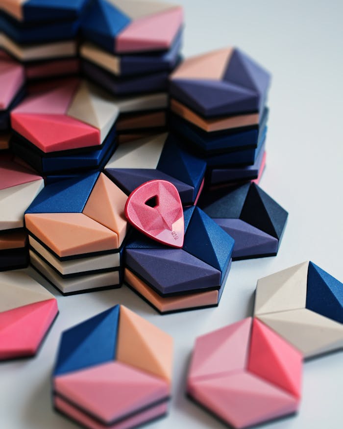 Vibrant geometric stacks with a red guitar pick on a white background.