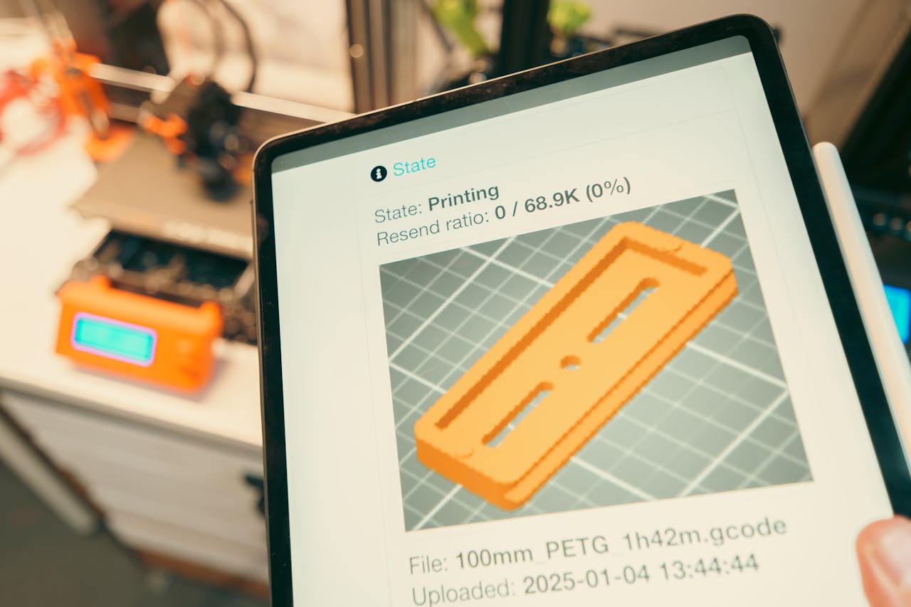 Close-up of a digital tablet displaying a 3D printing process in a workshop setting.